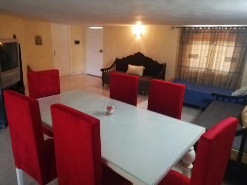 a dining room with a white table and red chairs at Belle maison bord de mer rdc in El Haouaria