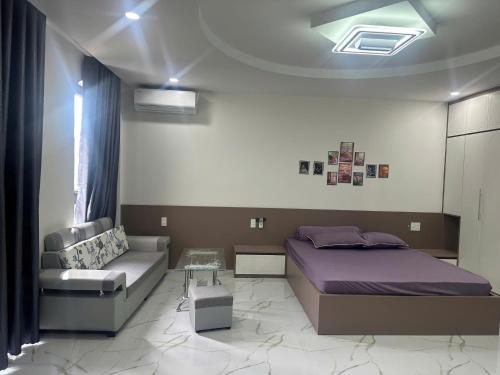a bedroom with a bed and a couch at Flower Apartment in Buôn Enao
