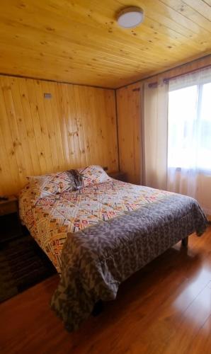 a bedroom with a bed in a wooden room at Cabañas Chiloé in Dalcahue