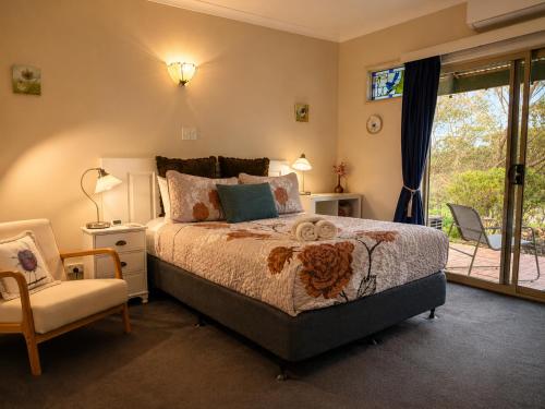 a bedroom with a bed and a chair and a window at Pecan Hill BNB in Toodyay