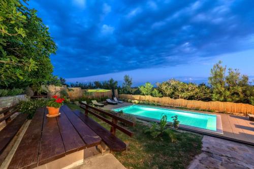 a backyard with a wooden bench and a swimming pool at My Dalmatia - Apartment Nostromo in Pag