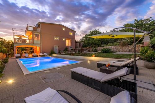 a home with a swimming pool and an umbrella at My Dalmatia - Apartment Nostromo in Pag