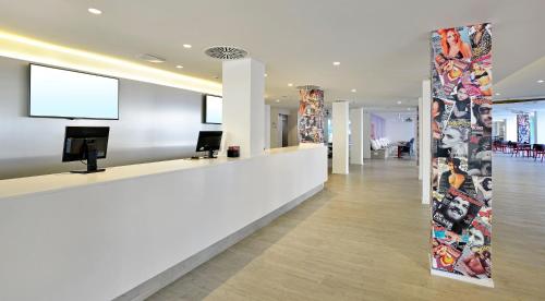 a lobby with a white counter with a tv on the wall at SOL by Meliá House Mallorca - Adults Only in Magaluf
