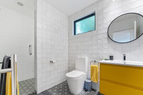 a bathroom with a toilet and a sink and a mirror at Totara tree house in Nelson