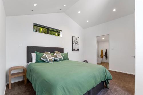 a bedroom with a bed with a green blanket at Totara tree house in Nelson