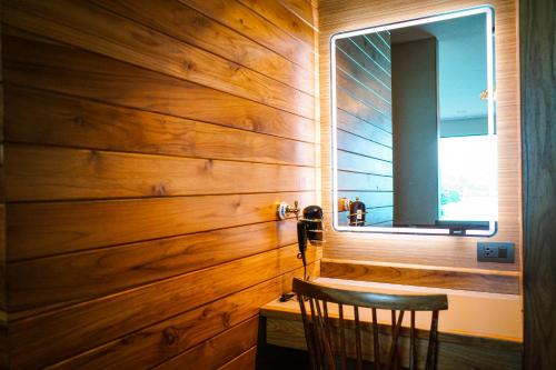 a wooden wall in a room with a chair and a mirror at Salty Pearl Beach Front Phuket in Patong Beach