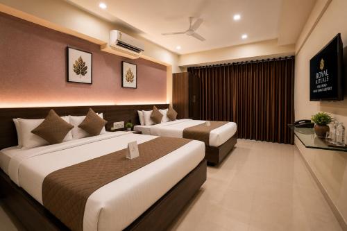 a hotel room with two beds and a television at Hotel Royal Rituals in Surat