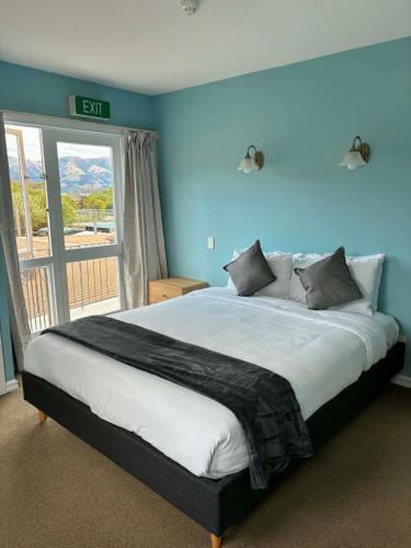 a bedroom with a large bed with blue walls at The Grand Hotel & Bar - Akaroa in Akaroa