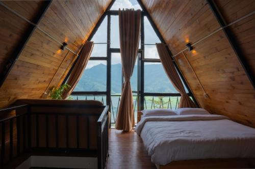 two beds in a room with a large window at The Edge Villa & Retreat in Pokhara