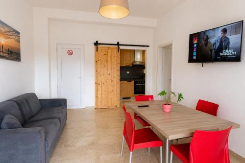 a living room with a couch and a table with red chairs at Carducci Mare e Monti in Pescara