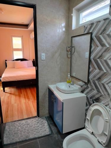 a bathroom with a sink and a toilet and a bed at Zensole Resort in Tarlac