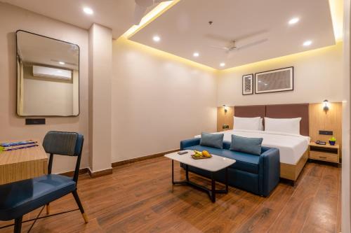 a hotel room with a bed and a couch and a table at Saltstayz Premier - Noida Sector 15 in Noida