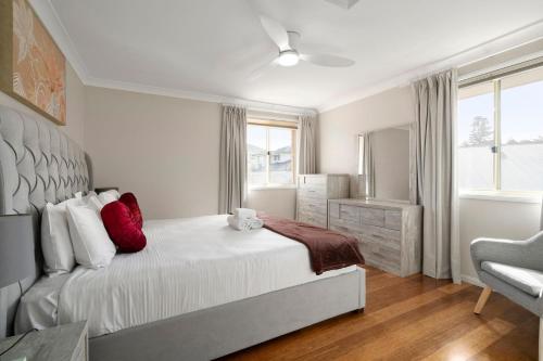 a white bedroom with a bed and a chair at Drumbern Pool House Macquarie Links in Ingleburn