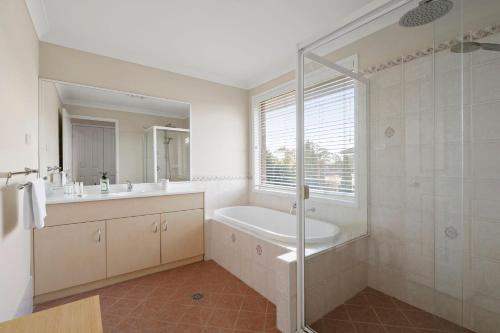 a bathroom with a tub and a sink and a shower at Drumbern Pool House Macquarie Links in Ingleburn