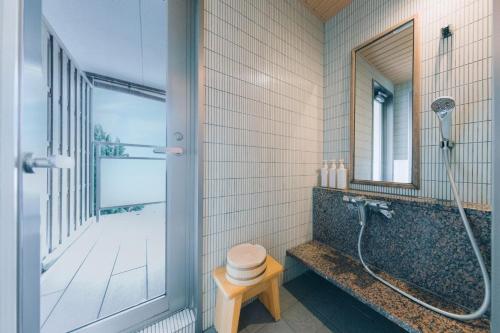 a bathroom with a shower and a toilet and a mirror at Toba Grand Hotel in Toba