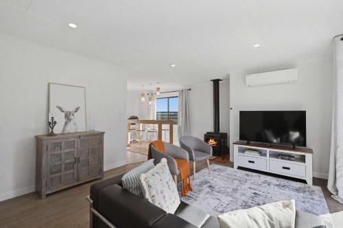 a living room with a couch and a flat screen tv at The Aurora House - BBQ Firepit Stargazing in Tea Tree