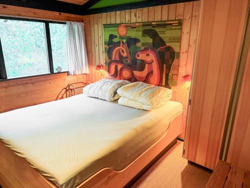 a bed in a room with a painting on the wall at Architectdesigned 1976 Summer House Near Beach in Store Fuglede