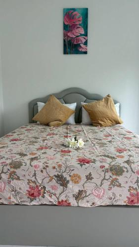 a bed with a floral bedspread with flowers on it at Aysaii Home02 in Panwa Beach
