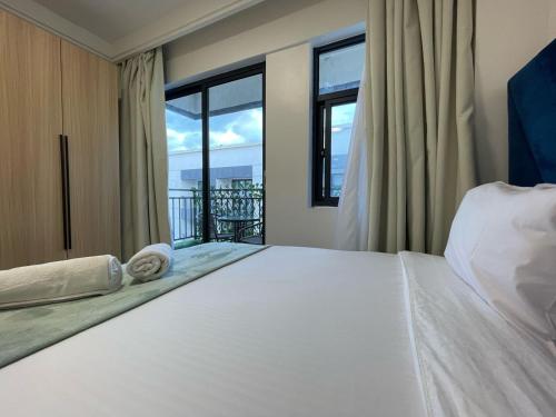 ein Schlafzimmer mit einem großen Bett und einem großen Fenster in der Unterkunft Sunset Stays near UN, Two Rivers & Village Market with Gym & Pool in Ruaka