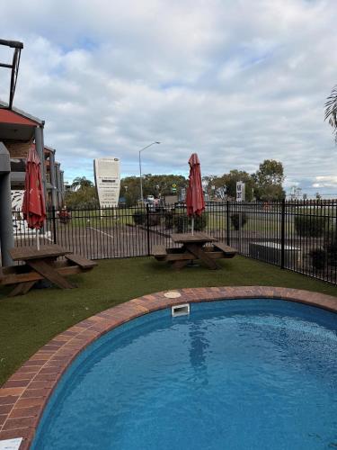 a swimming pool with a picnic table and two umbrellas at Bribie Waterways Motel in Bongaree