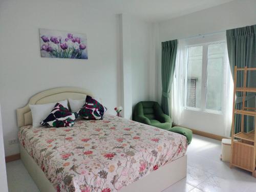 a bedroom with a bed and a green chair and a window at Aysaii Home01 in Panwa Beach