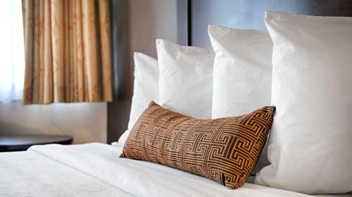 een bed met witte kussens en een kussen erop bij Aiden Los Angeles Downtown Dragon Gate Inn in Los Angeles
