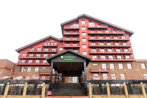 a large red building with a sign that reads university guest at Wyndham Garden Burabay in Borovoye