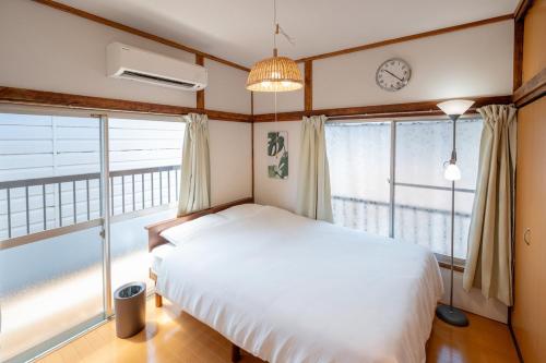 a bedroom with a bed and a clock on the wall at Kokonimo Niiza in Niizo