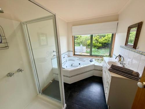 a bathroom with a tub and a shower and a window at Devils Gap in Currie