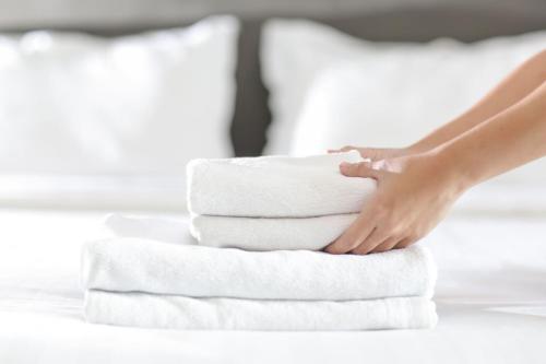 a woman is stacking towels on a bed at Cambridge Narrowboats - Beautiful New Moon Narrowboat in Cambridge