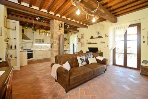 a living room with a brown couch and a kitchen at Dimora Belfiore - Happy Rentals in Capolona