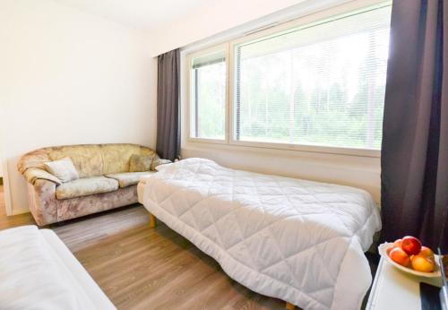 a bedroom with a bed and a couch and a window at Helmiapartments Sotkamo in Sotkamo