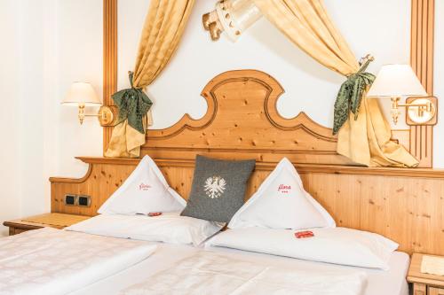 a bed with two white pillows on it at Hotel Flora in Selva di Val Gardena