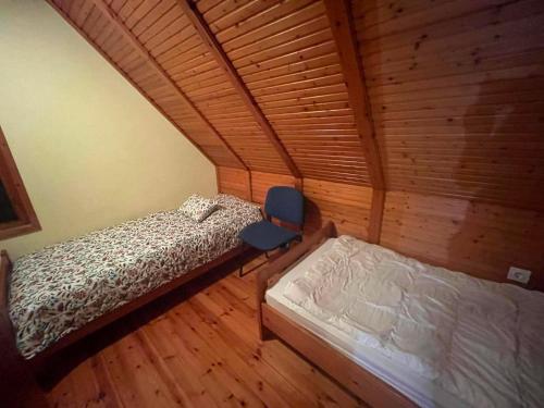 a bedroom with two beds and a chair in a room at Templomzugi Fenyő Nyaraló in Gyomaendrőd