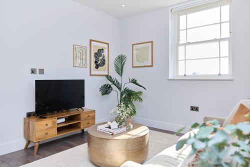 a living room with a flat screen tv and a table at Second Storey at Kew in Kew Bridge