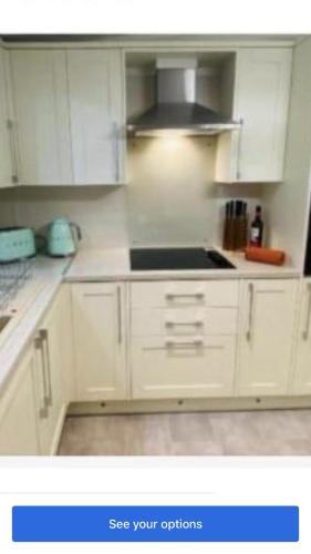 a kitchen with white cabinets and a stove top oven at Lakeside in Carrowmoreknock