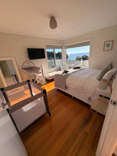 a bedroom with a large bed and a large window at Penguin Beach House in Penguin