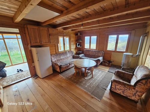 a living room with couches and a table and a refrigerator at Ранч ДИМ in Ivanjica