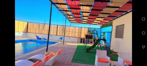 a swimming pool with a playground and a swimming pool at Albaraka-farm in Az Zarqa