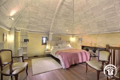 a bedroom with a large bed and two chairs at La tour carrée in Trimer