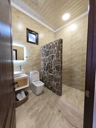 a bathroom with a toilet and a sink with a stone wall at LerHouseDilijan in Dilijan