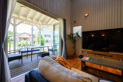 a living room with a couch and a flat screen tv at Aoshima Surfers House in Miyazaki
