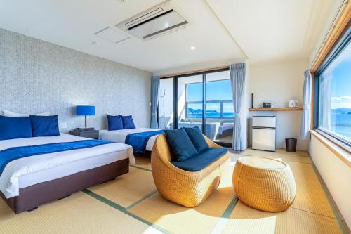 a bedroom with two beds and a chair and a window at SEVEN SEAS HOTEL ITO (セブンシーズホテル） in Ito
