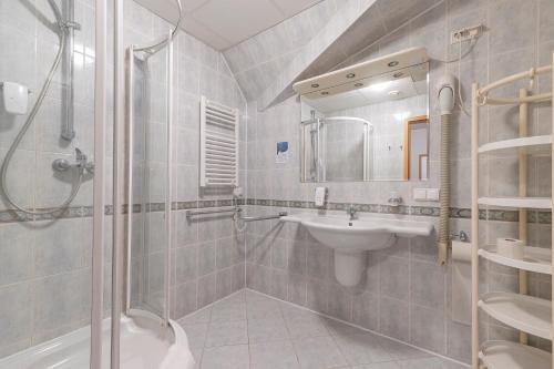 a bathroom with a shower and a sink and a mirror at Hotel Perła Bieszczadów Geovita in Czarna