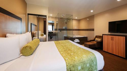 a bedroom with a large bed and a bathroom at Best Western Plus Glendale in Glendale