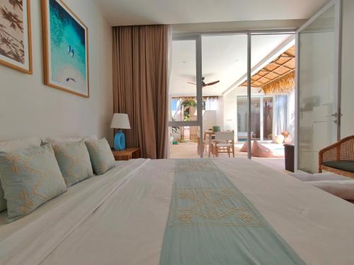 a bedroom with a large white bed and a living room at Villa Chioni Uluwatu by LODGELINK BALI in Uluwatu