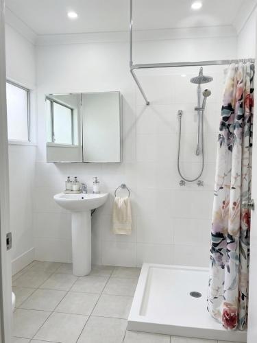 a white bathroom with a sink and a shower at ALRA2 Accommodations in Brisbane