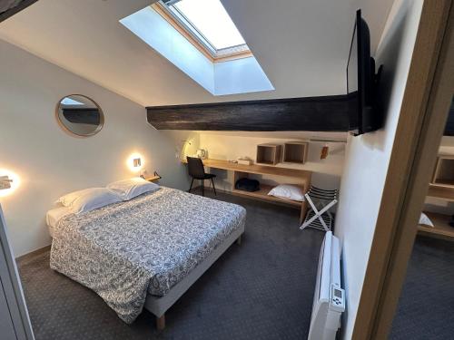 a bedroom with a bed and a skylight at Mauguio Center Hôtel in Mauguio