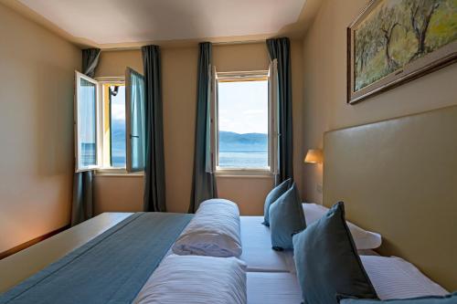 a bedroom with two beds and a large window at Hotel Baia D'Oro - Adults Only in Gargnano