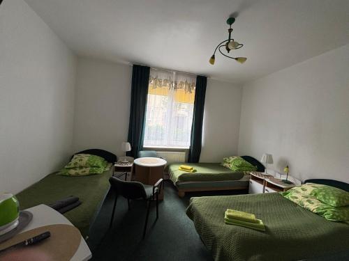 a room with two beds and a table and a window at Bursztynek in Gdynia